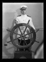 Naval officer posed behind a ship's wheel