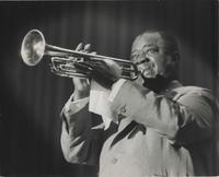 Louis Armstrong playing trumpet on-stage