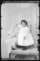 Studio portrait of young girl standing on a wicker couch.