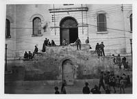 People hanging around outside entrance steps to large building