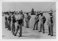 Group of nine men standing in two lines wearing pith helmets