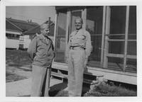 Two men standing in front of screened porch of building