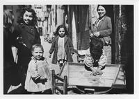 Group of six local women and children gathered on village street