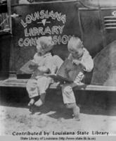 Two barefoot boys reading books outside of the bookmobile in tri parish area in Louisiana around 1940