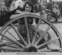 Woman leaning on wagon wheel at  Acadian Village in Lafayette Louisiana in 1950s