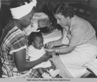 Mother holding baby girl as nurse gives her a vaccine