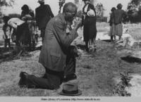 Man praying over grave in cemetery at New Roads Louisiana in 1938