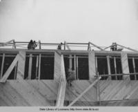 Men working on frame for Plaucheville Louisiana gymnasium under construction