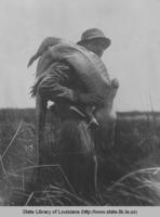Man with alligator slung over his shoulder around 1940