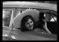 Young woman in an automobile and wearing a large straw hat